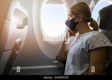 Frau trägt Gesichtsmaske im Flugzeug. Neue normale Reise Stockfoto