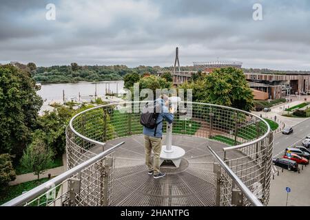 Mann Reisende beobachten PGE Nationalstadion, Wisla Fluss und Warschau durch Fernglas.Backpacker Sightseeing in Polen.Blick von der Universität Warschau Stockfoto