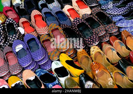 Bunte handgemachte Chappalls (Sandalen), die auf einem indischen Markt verkauft werden, handgefertigte Lederschuhe, traditionelle Schuhe. Stockfoto