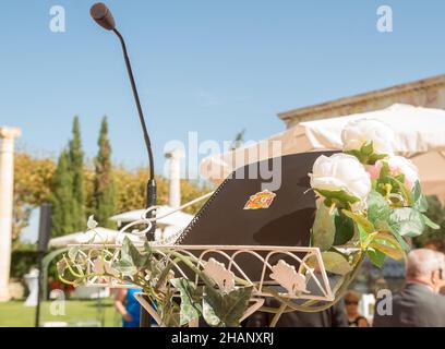 Heraldisches Design des spanischen Staatswappens auf dem Cover eines Notizbuchs, das sich an einem sonnigen Herbst auf einem Rednerpult neben einem Mikrofon im Freien befindet Stockfoto