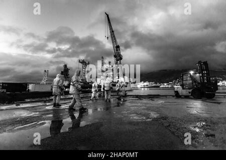 Arbeiter an einem Trockendock auf der alten BMV-Werft in Laksevaag, in der Nähe des Hafens von Bergen, Norwegen. Schiff bereit, das Dock zu verlassen. Die Royal Yacht im Hintergrund, p Stockfoto