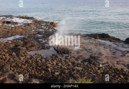 Ein Wasserstrahl, der durch ein Blowhole auf einem vulkanischen Schelf im Spouting Horn Beach Park am Südufer von Kauai, Hawaii, aufkommt Stockfoto