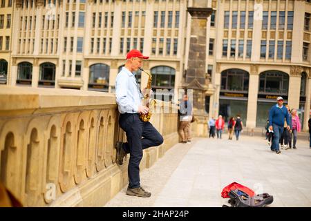 Ein Straßenmusiker spielt auf einer Stadtstraße das Saxophon. Berlin, Deutschland - 05.17.2019 Stockfoto