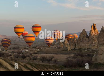 Dutzende von Heißluftballons mit Hunderten von Touristen, die am frühen Morgen in der Nähe von Goreme, Kappadokien, Zentralanatolien, Türkei, abheben Stockfoto