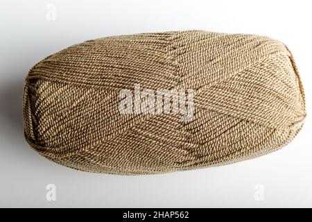 Ein hellbraunes Strickgarn aus Wolle zum Nähen oder aus Stickerei isoliert auf einem weißen Tisch, Seitenansicht von textilen Materialien Stockfoto