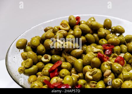 Eine Glasschüssel mit zerkleinerten grünen Oliven, gewürzt mit Öl und Chili Stockfoto