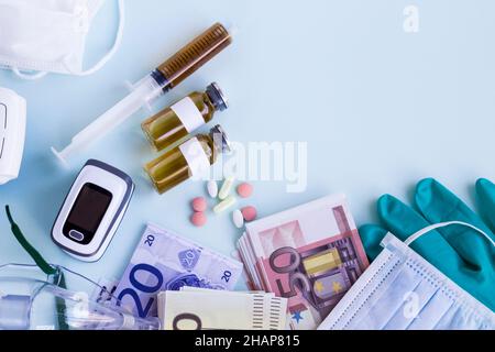 Impfstoffflaschen, Spritzen, medizinische Geräte auf hellblauer Oberfläche mit Euro-Banknoten und Kopieplatz Stockfoto