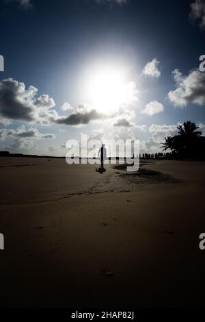 Silhouette eines erwachsenen Mannes, der am Strand läuft. Ruhige oder depressive Haltung an einem einsamen Strand Stockfoto