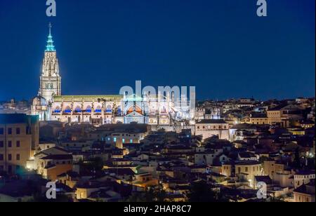 Nachtansicht der Kathedrale von Toledo, beleuchtet mit Häusern um sie herum Stockfoto