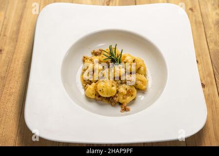 Kartoffel-Gnocchi gewürzt mit Wurst ragù in einem weißen Gericht auf Holztisch Stockfoto