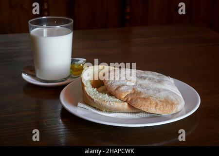 Frisch gebackener Brotmuffin zum Frühstück mit einem Glas Milch und Olivenöl, typisch für andalusien. Spanien, europa Stockfoto
