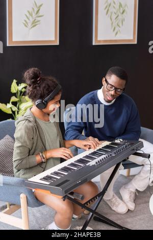 Zeitgenössische biracial Schülerin und ihre Musiklehrerin der afrikanischen Ethnie spielen Musik Keyboard Stockfoto
