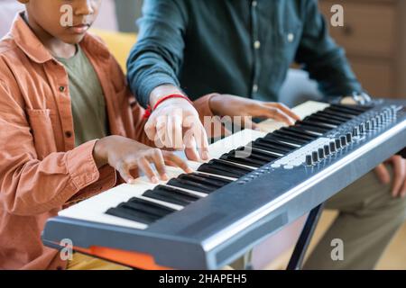 Hand des jungen Musiklehrers, der während des Unterrichts in der häuslichen Umgebung auf eine der Tasten des Klaviertastatur zeigt Stockfoto