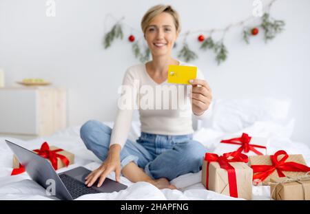 Weihnachtsgeschäfte. Lächelnde Dame mit Laptop und Kreditkarte Stockfoto