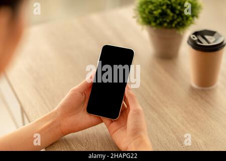 Weibliche Hände halten Smartphone mit leerem Bildschirm mit Mockup für Werbung oder Website-Design Stockfoto