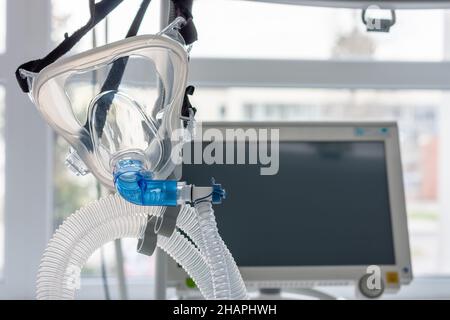 Gesichtsmaske mit nichtinvasiver Beatmung, auf dem Hintergrund medizinisches Beatmungsgerät auf der Intensivstation im Krankenhaus. Stockfoto