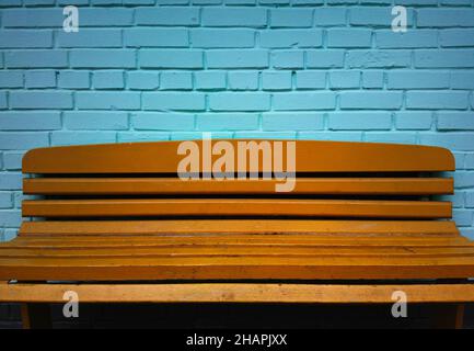Orangefarbene Bank mit türkisblauem Mauerwerk Stockfoto