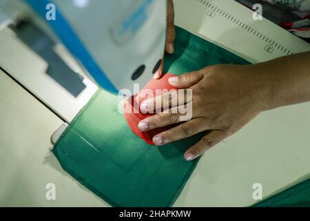 Ein Arbeiter näht die Nationalflagge von Bangladesch vor dem Siegesstag in Narayanganj, am Stadtrand von Dhaka, Bangladesch, am 14. Dezember 2021. Am 16. Dezember wurde zum Gedenken an den Sieg der Streitkräfte Bangladeschs über die pakistanischen Streitkräfte im Befreiungskrieg von Bangladesch im Jahr 1971 ein Siegestag gefeiert. Der Kommandeur der pakistanischen Streitkräfte, General AAK Niazi, gab sich mit seinen Truppen den alliierten Kräften von Bangladesch hin, was das Ende des 9 Monate andauernden Bangladesh Liberation war und 1971 den Völkermord in Bangladesch und die offizielle Abspaltung Ostpakistans nach Bangladesch bedeutete. (Foto von Stockfoto