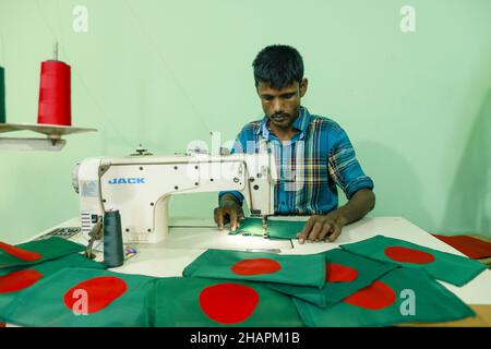 Ein Arbeiter näht die Nationalflagge von Bangladesch vor dem Siegesstag in Narayanganj, am Stadtrand von Dhaka, Bangladesch, am 14. Dezember 2021. Am 16. Dezember wurde zum Gedenken an den Sieg der Streitkräfte Bangladeschs über die pakistanischen Streitkräfte im Befreiungskrieg von Bangladesch im Jahr 1971 ein Siegestag gefeiert. Der Kommandeur der pakistanischen Streitkräfte, General AAK Niazi, gab sich mit seinen Truppen den alliierten Kräften von Bangladesch hin, was das Ende des 9 Monate andauernden Bangladesh Liberation war und 1971 den Völkermord in Bangladesch und die offizielle Abspaltung Ostpakistans nach Bangladesch bedeutete. (Foto von Stockfoto