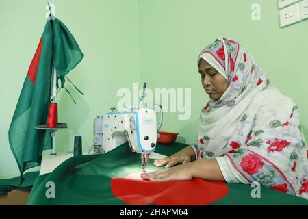 Ein Arbeiter näht die Nationalflagge von Bangladesch vor dem Siegesstag in Narayanganj, am Stadtrand von Dhaka, Bangladesch, am 14. Dezember 2021. Am 16. Dezember wurde zum Gedenken an den Sieg der Streitkräfte Bangladeschs über die pakistanischen Streitkräfte im Befreiungskrieg von Bangladesch im Jahr 1971 ein Siegestag gefeiert. Der Kommandeur der pakistanischen Streitkräfte, General AAK Niazi, gab sich mit seinen Truppen den alliierten Kräften von Bangladesch hin, was das Ende des 9 Monate andauernden Bangladesh Liberation war und 1971 den Völkermord in Bangladesch und die offizielle Abspaltung Ostpakistans nach Bangladesch bedeutete. (Foto von Stockfoto