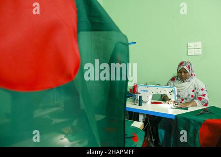 Ein Arbeiter näht die Nationalflagge von Bangladesch vor dem Siegesstag in Narayanganj, am Stadtrand von Dhaka, Bangladesch, am 14. Dezember 2021. Am 16. Dezember wurde zum Gedenken an den Sieg der Streitkräfte Bangladeschs über die pakistanischen Streitkräfte im Befreiungskrieg von Bangladesch im Jahr 1971 ein Siegestag gefeiert. Der Kommandeur der pakistanischen Streitkräfte, General AAK Niazi, gab sich mit seinen Truppen den alliierten Kräften von Bangladesch hin, was das Ende des 9 Monate andauernden Bangladesh Liberation war und 1971 den Völkermord in Bangladesch und die offizielle Abspaltung Ostpakistans nach Bangladesch bedeutete. (Foto von Stockfoto