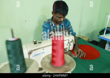 Ein Arbeiter näht die Nationalflagge von Bangladesch vor dem Siegesstag in Narayanganj, am Stadtrand von Dhaka, Bangladesch, am 14. Dezember 2021. Am 16. Dezember wurde zum Gedenken an den Sieg der Streitkräfte Bangladeschs über die pakistanischen Streitkräfte im Befreiungskrieg von Bangladesch im Jahr 1971 ein Siegestag gefeiert. Der Kommandeur der pakistanischen Streitkräfte, General AAK Niazi, gab sich mit seinen Truppen den alliierten Kräften von Bangladesch hin, was das Ende des 9 Monate andauernden Bangladesh Liberation war und 1971 den Völkermord in Bangladesch und die offizielle Abspaltung Ostpakistans nach Bangladesch bedeutete. (Foto von Stockfoto