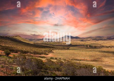 Blick bei Sonnenuntergang über die Weite des australischen Outback vom Buckaringa North Camp Site über der Depot Flat bis zu den South Flinders Ranges gegen sk Stockfoto