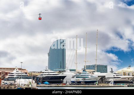 Seilbahn, die zum Berg Montjuic in Barcelona hinauffährt und über den Trockendock des Hafens von Barcelona mit Luxusyachten fährt Stockfoto