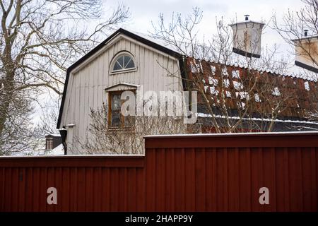Traditionelle Holzarchitektur Schwedens. Weißes Holzhaus mit braunem Ziegeldach und dunkelrotem Zaun. Hauptstadt von Schweden, Stockholm. Stockfoto