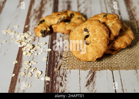 Einige hausgemachte Honig Rosinen Haferflocken und ein taumelter Haferflocken auf dem abgenutzten Holztisch. Konzept der natürlichen und gesunden Ernährung. Stockfoto