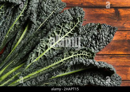 Frische schwarze Kohlblätter auf Holzgrund. Schwarzer Grünkohl. Italienisches Essen. Stockfoto