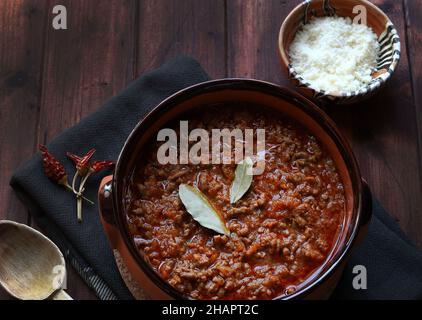 Hausgemachte Bolognese- oder ragù-Sauce in rustikaler Schüssel, auf dunklem Holz serviert. Direkt darüber. Stockfoto