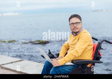 Ein Mann mit Behinderungen im Rollstuhl, der mit Dokumenten arbeitet Stockfoto
