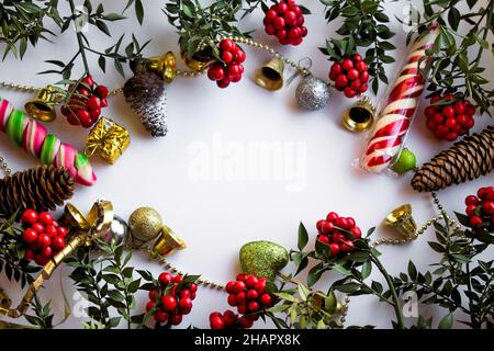 Schöner weihnachtsrahmen mit handgefertigten roten Blumen, kokina, Süßigkeiten und weihnachtsschmuck auf weißem Hintergrund mit Kopierraum Stockfoto