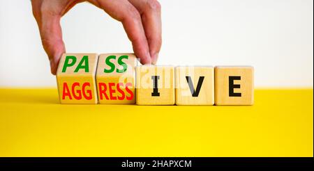 Passives oder aggressives Symbol. Geschäftsmann dreht Holzwürfel und ändert das Wort passiv in aggressiv. Schöner weißer Hintergrund, Kopierbereich. Busin Stockfoto