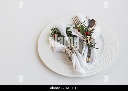 Weihnachten oder Neujahr Menüservice mit stilvollen, weißen Stoffservietten, Serviettenringen und Besteckset in Teller auf Weiß Stockfoto