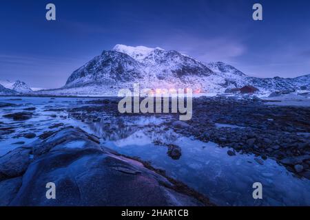 Küste mit Steinen und schneebedeckten Berg im Winter Stockfoto