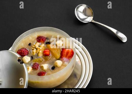 Traditionelles türkisches Dessert Asure oder Noah's Ark Pudding auf schwarzer Oberfläche mit Löffel und Kopierraum Stockfoto