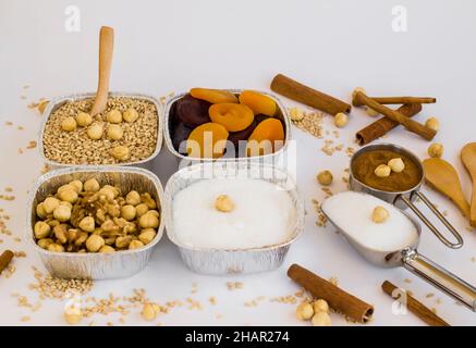 Ungekochte Zutaten von traditionellem Dessert Asure, Noah Puding in Aluminiumschüsseln, Folienbehältern – zum Mitnehmen auf der weißen Oberfläche Stockfoto