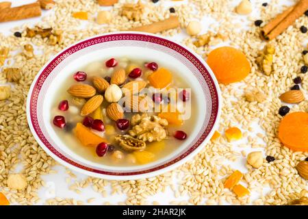 Traditionelles türkisches Dessert Ashure oder Noah's Pudding in einer weißen Schüssel auf ungekochten ashura-Zutaten Stockfoto