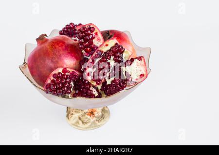 Reife, frische Granatapfel-Früchte in stilvoller Glasschale auf weißer Oberfläche mit Kopierfläche geschnitten Stockfoto