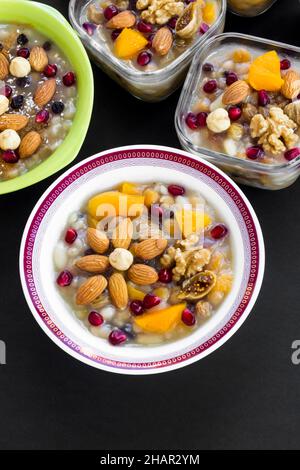 Traditionelles türkisches Dessert Asure oder Noah's Ark Pudding auf schwarzer Oberfläche, vertikales Bild Stockfoto