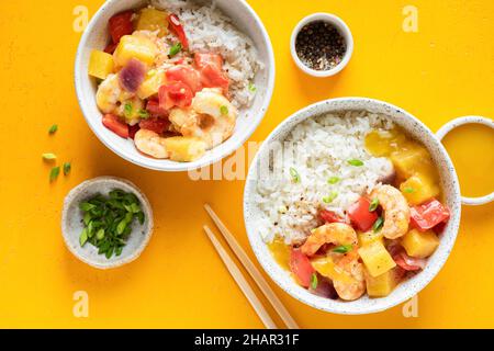 Weißer Reis mit Garnelen und Ananas in einer Schüssel auf gelbem Hintergrund, Draufsicht Stockfoto