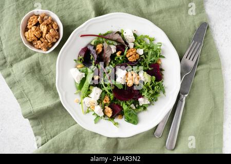 Gesunder Rübensalat mit Feta und Walnüssen auf weißem Teller, Tischansicht Stockfoto