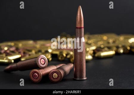 Kupfer-Maschinengewehr Kugeln, verschwommene gelbe Ammo auf schwarzem Brett Hintergrund Stockfoto