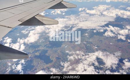 Blick vom Passagierfenster des Verkehrsflugzeugs, verschwommene bergige afrikanische Landschaft unter dem Flugzeugflügel sichtbar Stockfoto