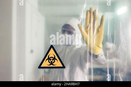 Biohazard-Symbol mit nicht erkennbarem Arzt, der den Durchgang verbietet Stockfoto