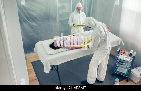 Ärzte entnehmen Blutprobe von Patienten, die auf einer Liege liegen Stockfoto