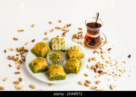 Traditionelles türkisches Gebäck, trockenes Dessert, Baklava auf weißem Teller mit Pistazien-Nüssen. Serviert mit türkischem Tee Stockfoto