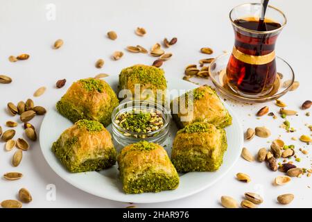 Traditionelles türkisches Gebäck, trockenes Dessert, Baklava auf weißem Teller mit Pistazien-Nüssen. Serviert mit türkischem Tee Stockfoto